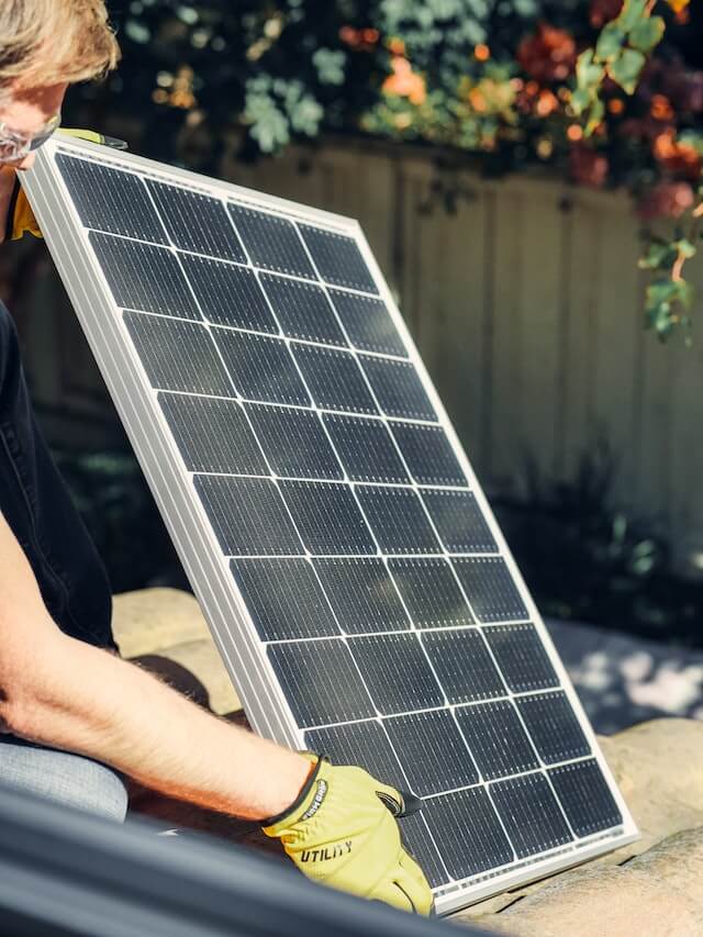 Panel solar sostenido por un técnico con guantes de trabajo